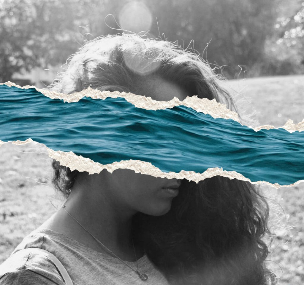 Fotografía de mujer en blanco y negro que se deja ver entre un recorte de olas del mar